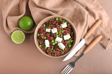 Bowl of tasty cooked lentils, beans and cheese on color background