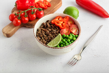 Bowl of tasty cooked lentils and vegetables on white background