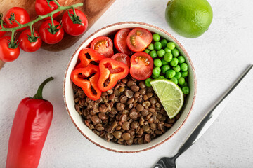 Bowl of tasty cooked lentils and vegetables on white background