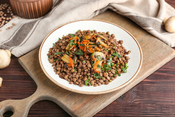 Plate with tasty cooked lentils and mushrooms on table