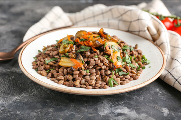 Plate with tasty cooked lentils and mushrooms on grunge background