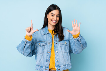 Young caucasian woman isolated on blue background counting seven with fingers