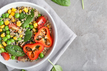 Bowl with healthy quinoa salad on grunge background