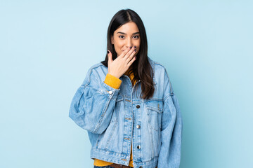 Young caucasian woman isolated on blue background happy and smiling covering mouth with hand