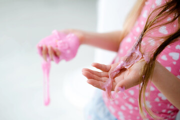 Naklejka premium A little girl stained her hair with slime. Child hair tangled in pink slime.
