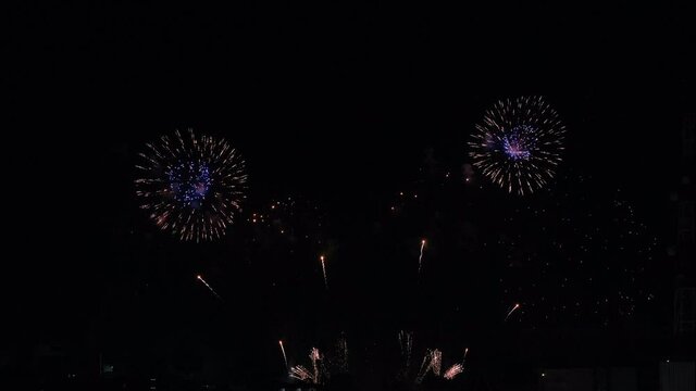 Display of real fireworks on dark background at night with multicolor and pattern during celebration or festival in city.
