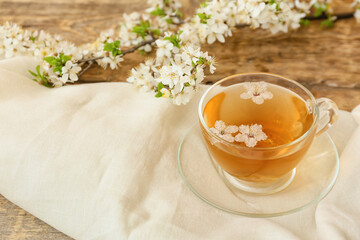 Cup with tasty tea and blooming branches on wooden table