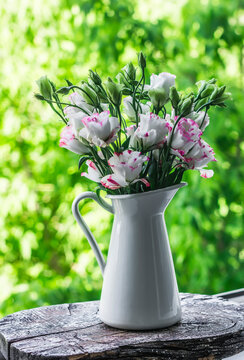Bouquet of eustom in a vintage metal jug on the window against the background of a summer green garden
