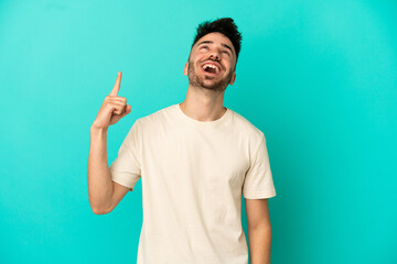 Fototapeta premium Young caucasian man isolated on blue background pointing up and surprised