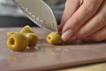 close-up: a girl cuts green olives with a knife