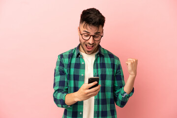 Young caucasian man isolated on pink background surprised and sending a message