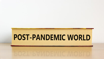 Covid-19 post-pandemic world symbol. Concept words 'post-pandemic world' on book on wooden table. Beautiful white background. Covid-19 post-pandemic world and medical concept.