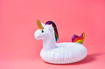 Inflatable white unicorn pool toy on pink background. Creative minimal concept