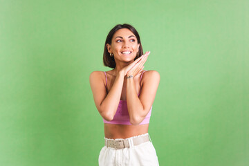 Woman in pink crop top and white trousers on green background stylish fit good shape happy positive excited cheerful posing