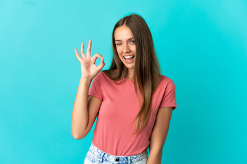 Young woman over isolated blue background showing ok sign with fingers