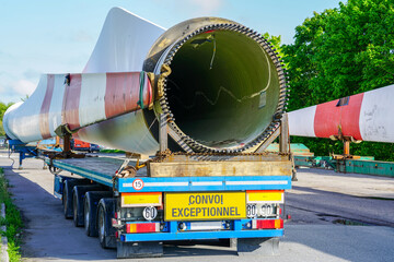 A view of a truck, a low-loader semi-trailer with oversized wind generator parts in the parking lot