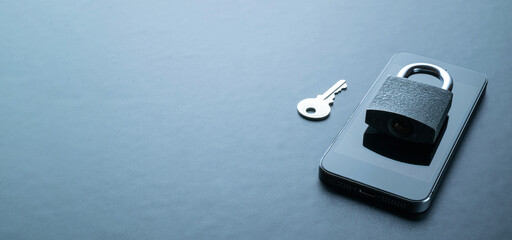 Internet protection. Modern space grey mobile phone with padlock, key on dark background. Darkweb,...