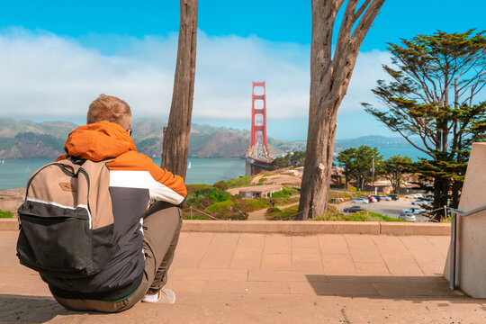 Young man in a jacket admiring the Golden Gate Bridge in San Francisco on a sunny day. San Francisco, USA - 17 Apr 2021
