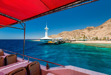 View from pleasure boat on underwater observatory building and beautiful coral reefs of the Red Sea, sandy beaches, tourist hotels and mountains,  Red Sea, Sinai, Middle East