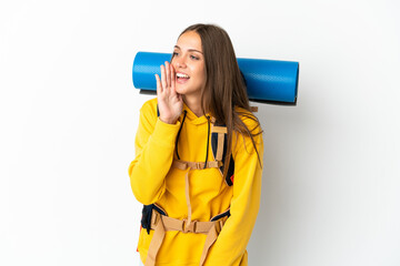 Young mountaineer woman with a big backpack over isolated white background shouting with mouth wide open to the side