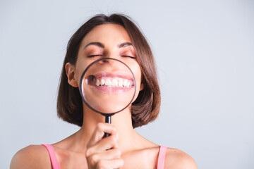 Pretty woman on gray background held magnifier happy showing white snow teeth smile