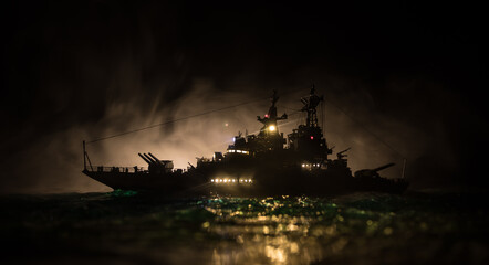 Silhouettes of a crowd standing at blurred military war ship on foggy background. Selective focus.