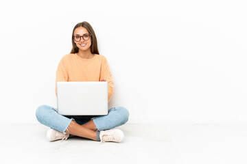 Naklejka premium Young woman with a laptop sitting on the floor keeping the arms crossed in frontal position