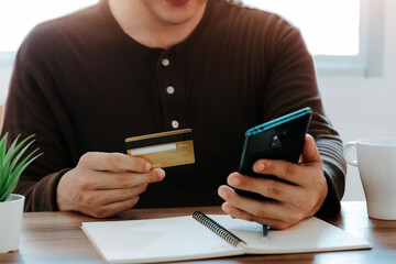 Young man using smart phone and credit card for shopping online in coffee shop cafe.
