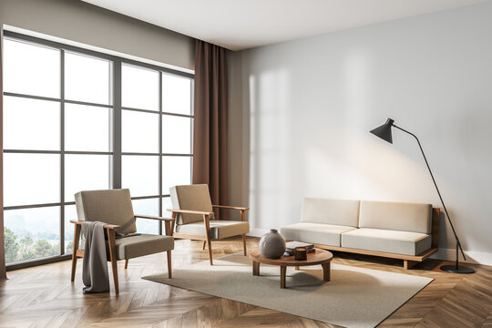 Light living room interior with armchairs and sofa, panoramic windows