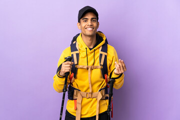 African American man with backpack and trekking poles over isolated background making money gesture