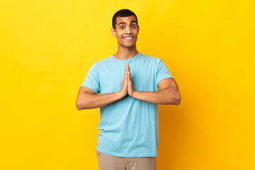 African American man over isolated background keeps palm together. Person asks for something