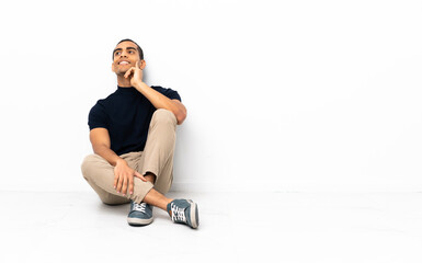 Fototapeta premium African American man sitting on the floor thinking an idea while looking up