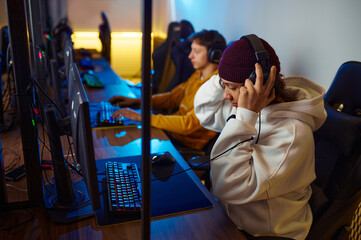 Fototapeta na wymiar Two young gamers in headsets play in video game club
