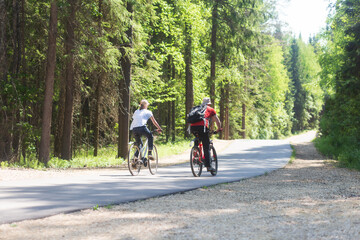 A man and a woman ride bicycles in the park in the summer.Outdoor fitness.