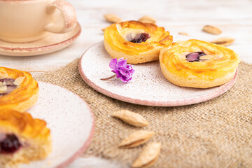 Small cheesecakes with jam and almonds with cup of coffee on a white wooden background. Side view, selective focus.