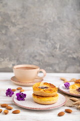 Small cheesecakes with jam and almonds with cup of coffee on a white wooden background. Side view, copy space.