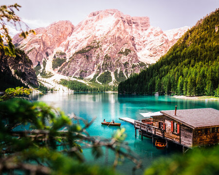 Lonely boat with man and woman on the Lago di Braies (Pragser Wildsee) with colorful water, wooden cottage and mountain in the background, Dolomites, Italy