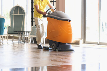 Man is cleaning hotel lobby with industrial vacuum cleaner