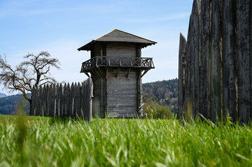 A reconstructed wooden Roman watchtower and a wooden border fence under a clear blue sky. This...