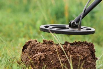 Coil of metal detector on background of ground and grass on meadow or field, searing coins, jewelry...