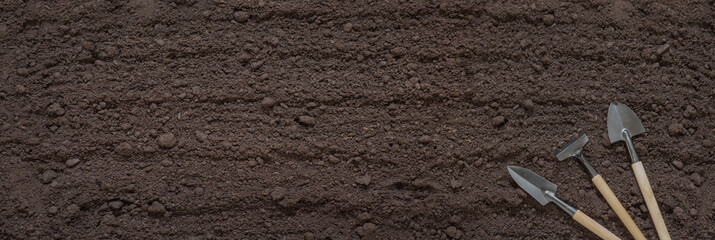soil and garden tools banner, texture of fertile soil close-up, top view, concept of agriculture,...