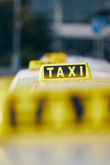 Selective focus on taxi sign on roof.; Car waiting for passenger in city street.