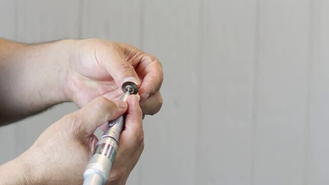The dentist polishes the surface of the metal-ceramic prosthesis.