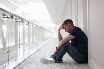 Frustrated, tired man sits in hallway under door