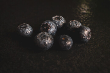 Wet blueberries on black cutting board. Forest berries with water drops on the table. Blueberries isolated. Summer harvest. Vitamin and antioxidant concept. Juicy dessert. Fresh ripe berries. 
