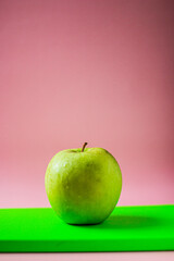 Close-up of green apple on a green notepad in pink background