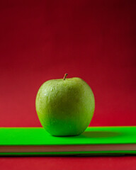 Close-up of green apple on a green notepad in red color background
