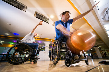 Two young disabled men in wheelchairs playing bowling in the club