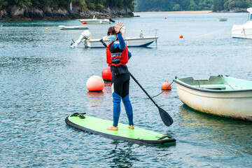 A young woman paddle surfing in the sea in Urdaibai, a Bizkaia biosphere reserve next to Mundaka....