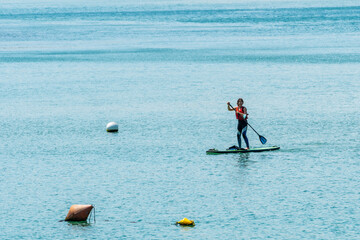 Fototapeta na wymiar A young woman paddle surfing in the sea in Urdaibai, a Bizkaia biosphere reserve next to Mundaka. Basque Country